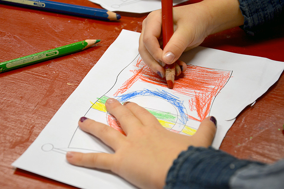 Ett barn ritar samiska flaggan.