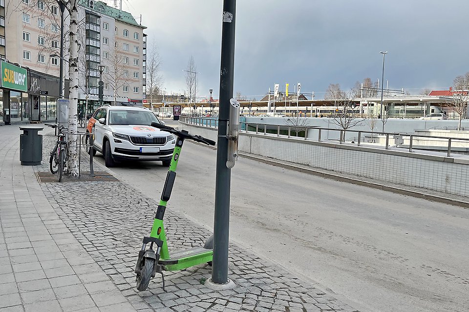 En grön elsparkcykel står parkerad på en parkeringsyta avsedd för cyklar, på Järnvägstorget i Umeå.